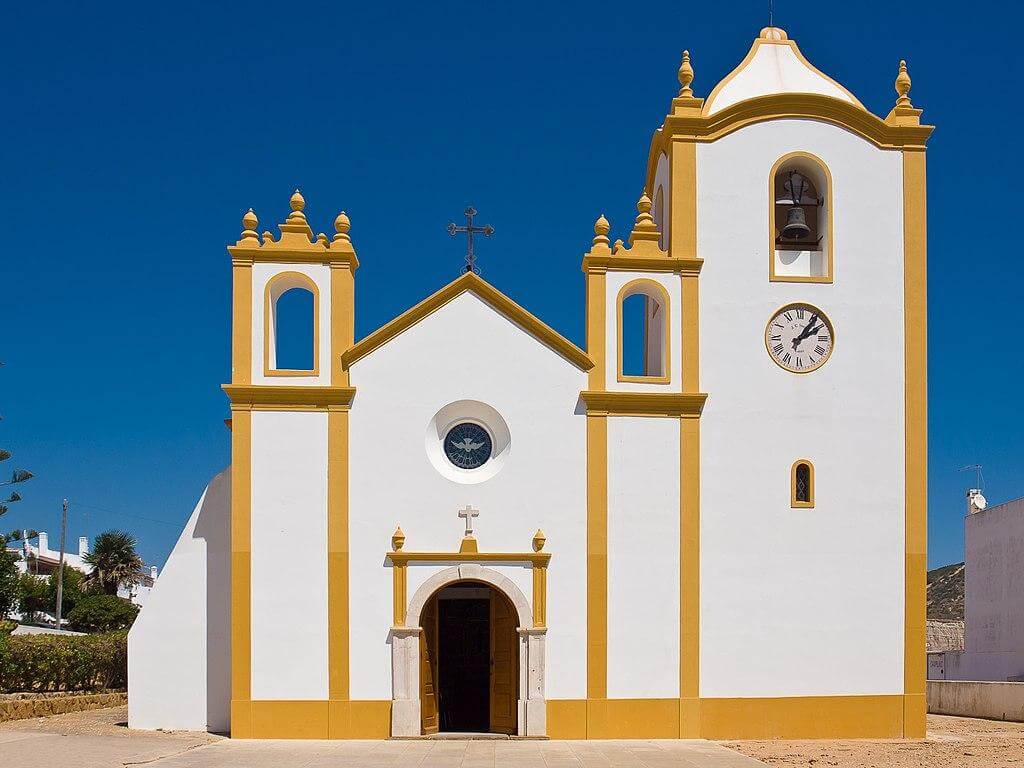 The historic white and yellow facade of the Church of Nossa Senhora da Luz near the sea