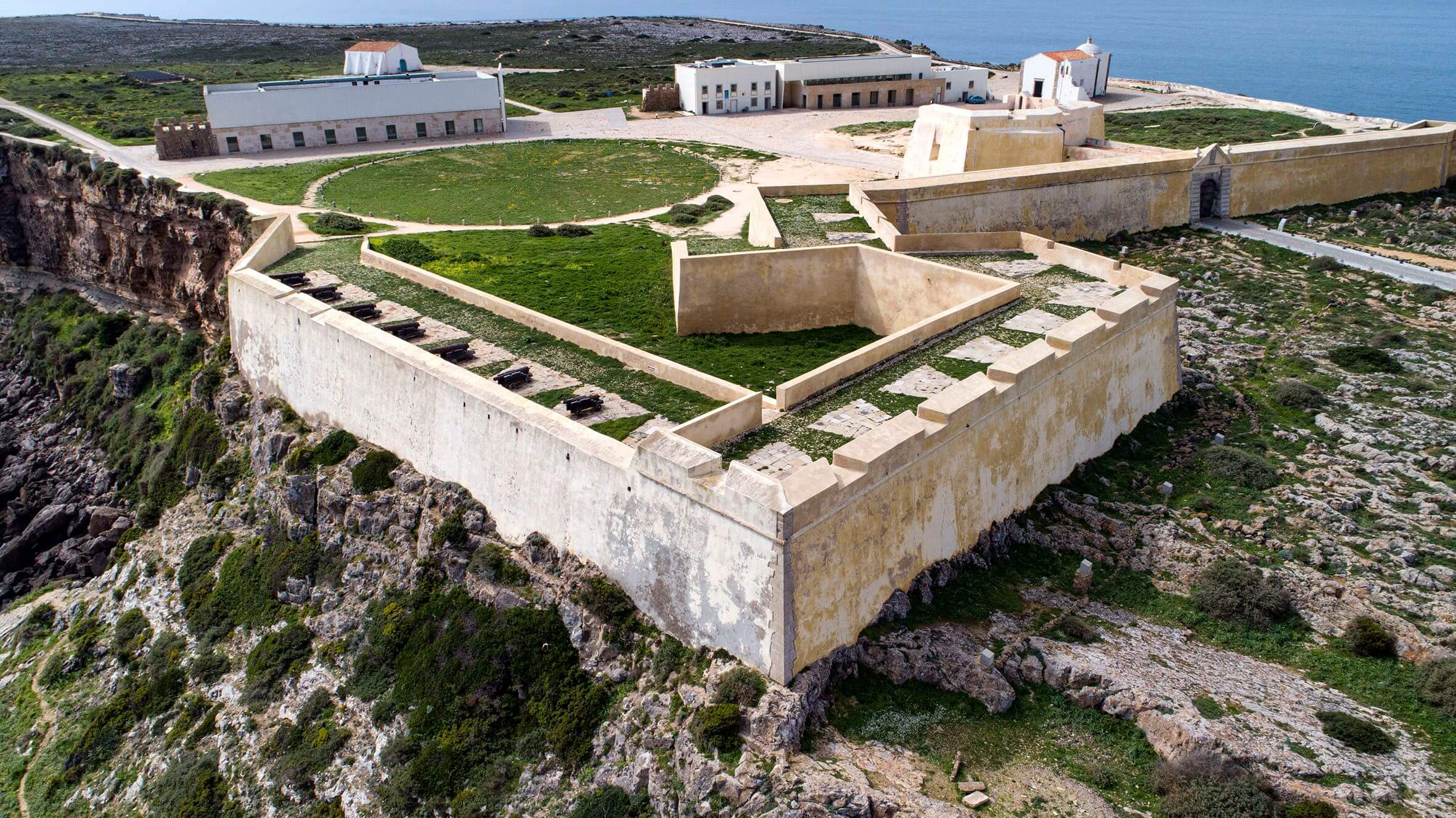 Aerial view of the dramatic, expansive sea cliffs stretching around the grand Fortaleza de Sagres headland site