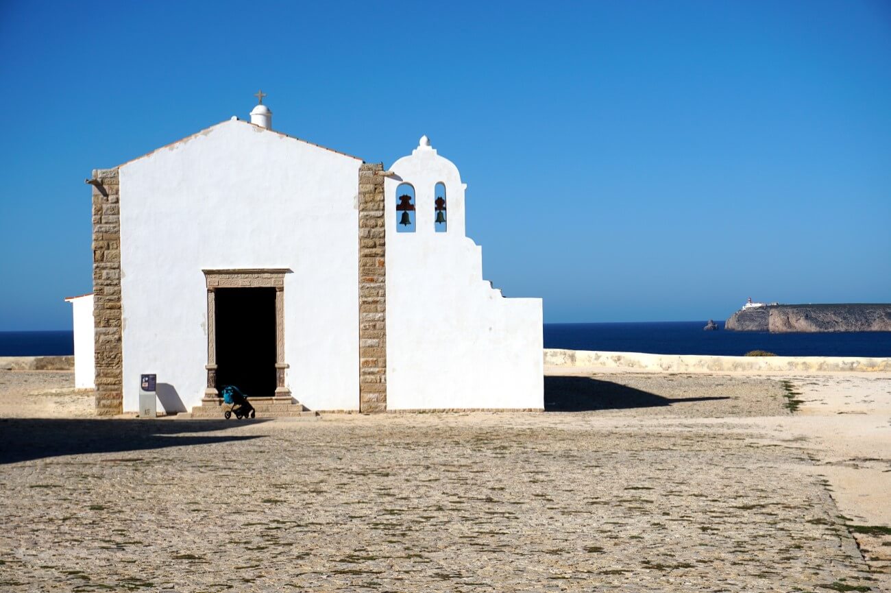 The clean, white stone facade of the historic Church of Our Lady of Grace located inside the Sagres Fortress grounds