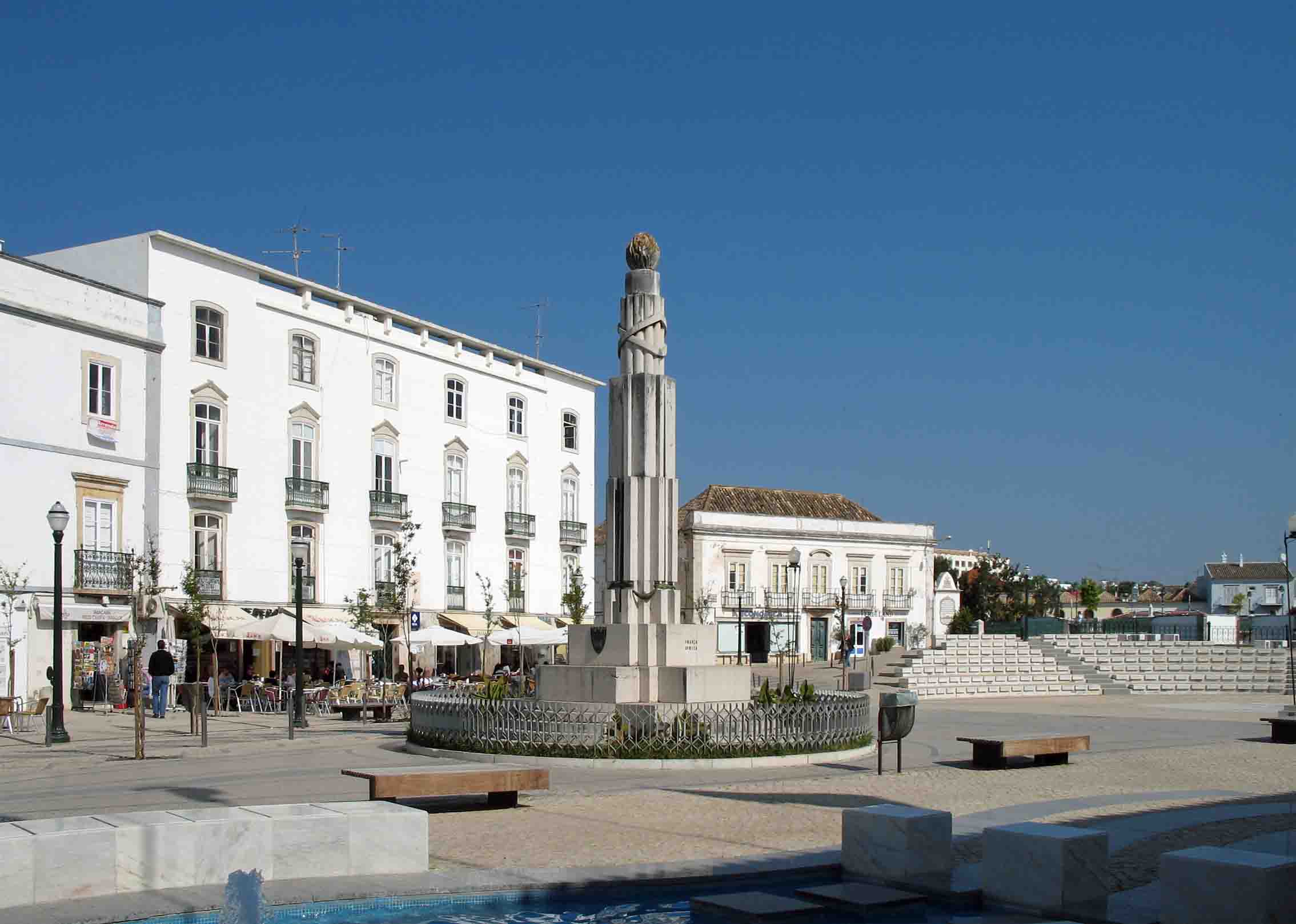 The central civic square of Praça da República in Tavira featuring traditional Portuguese calçada paving stones, outdoor cafes, and historical administrative buildings