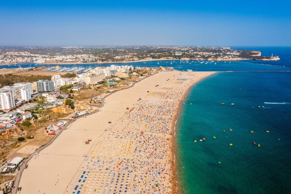 Stunning panoramic aerial perspective over the expansive golden sands and high-rise hotels of Praia da Rocha