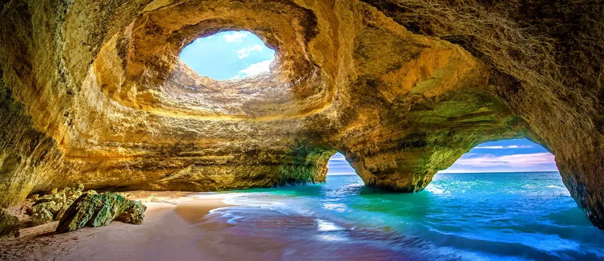 The striking naturally formed sunlit dome and sea opening of the iconic Benagil Cave along the coastal cliffs near Carvoeiro