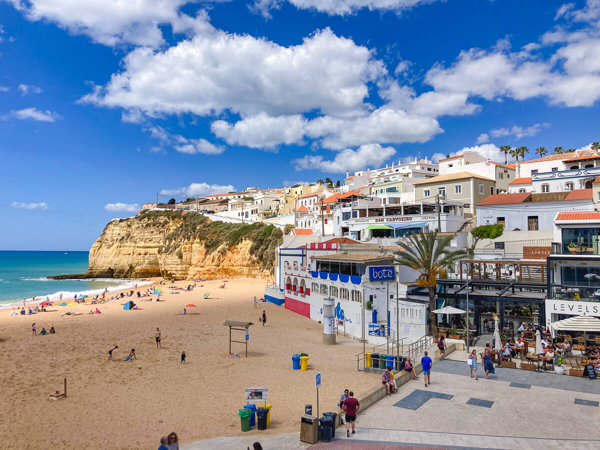 Scenic view of the golden sand beach and traditional white buildings clustered in the valley of Carvoeiro town centre
