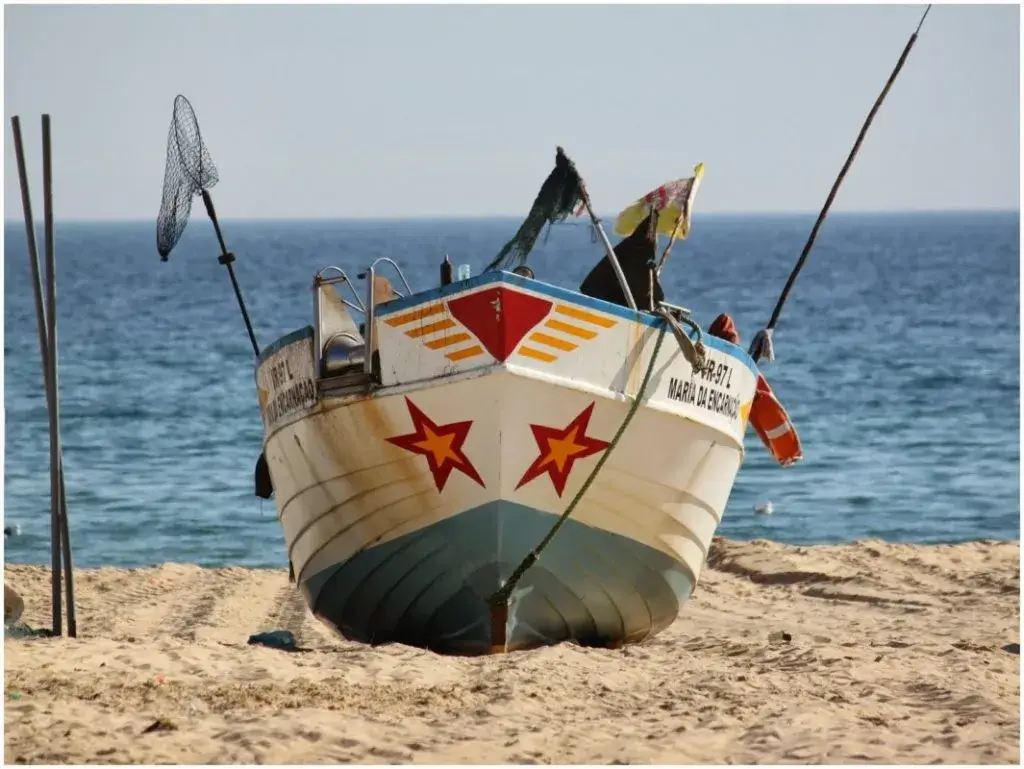 Traditional brightly colored Portuguese fishing boat resting on the open golden sands of Monte Gordo beach