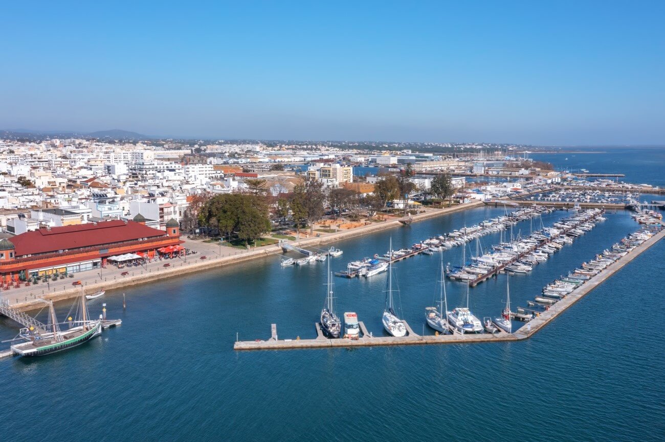 Pleasure boats and yachts docked along the modern pontoons of the Olhão Marina, right alongside the waterfront promenade