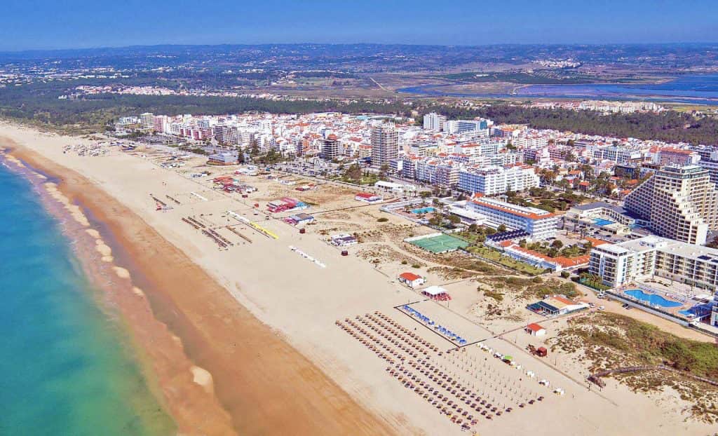 Expansive view of the wide golden sand beach and blue ocean at Praia de Monte Gordo, showing the accessible beachfront boardwalk