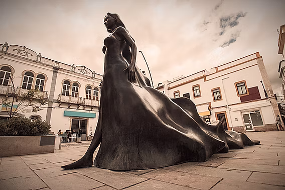 The iconic stone statue monument of the legendary Princess Floripes situated in a public square within the historic core of Olhão