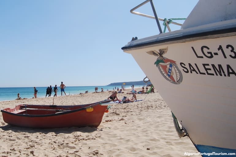 Traditional bright wooden fishing boat resting on the sand at Salema beach, showcasing the village heritage