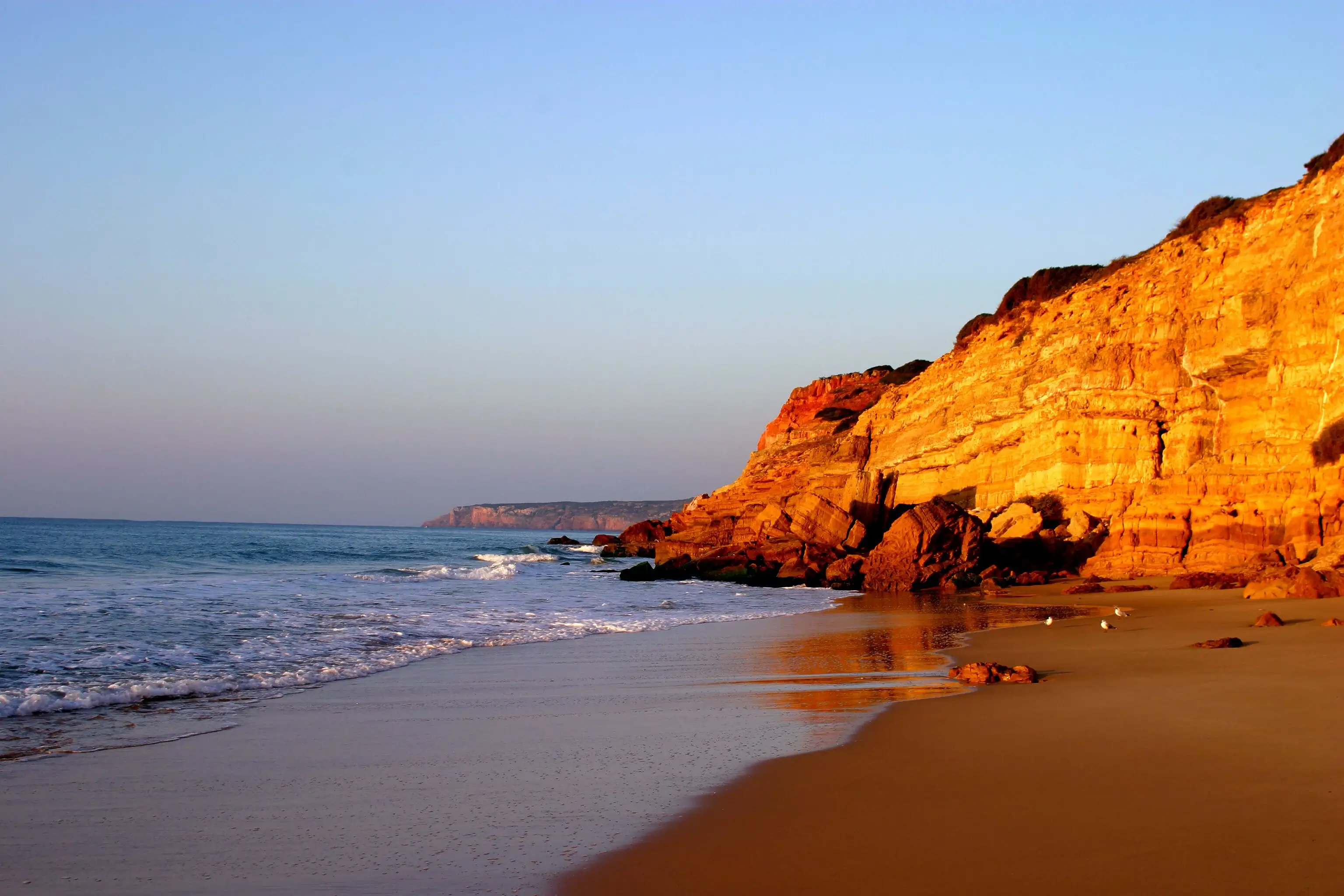 Golden limestone cliffs and tranquil waters at the main beach cove area of Salema village