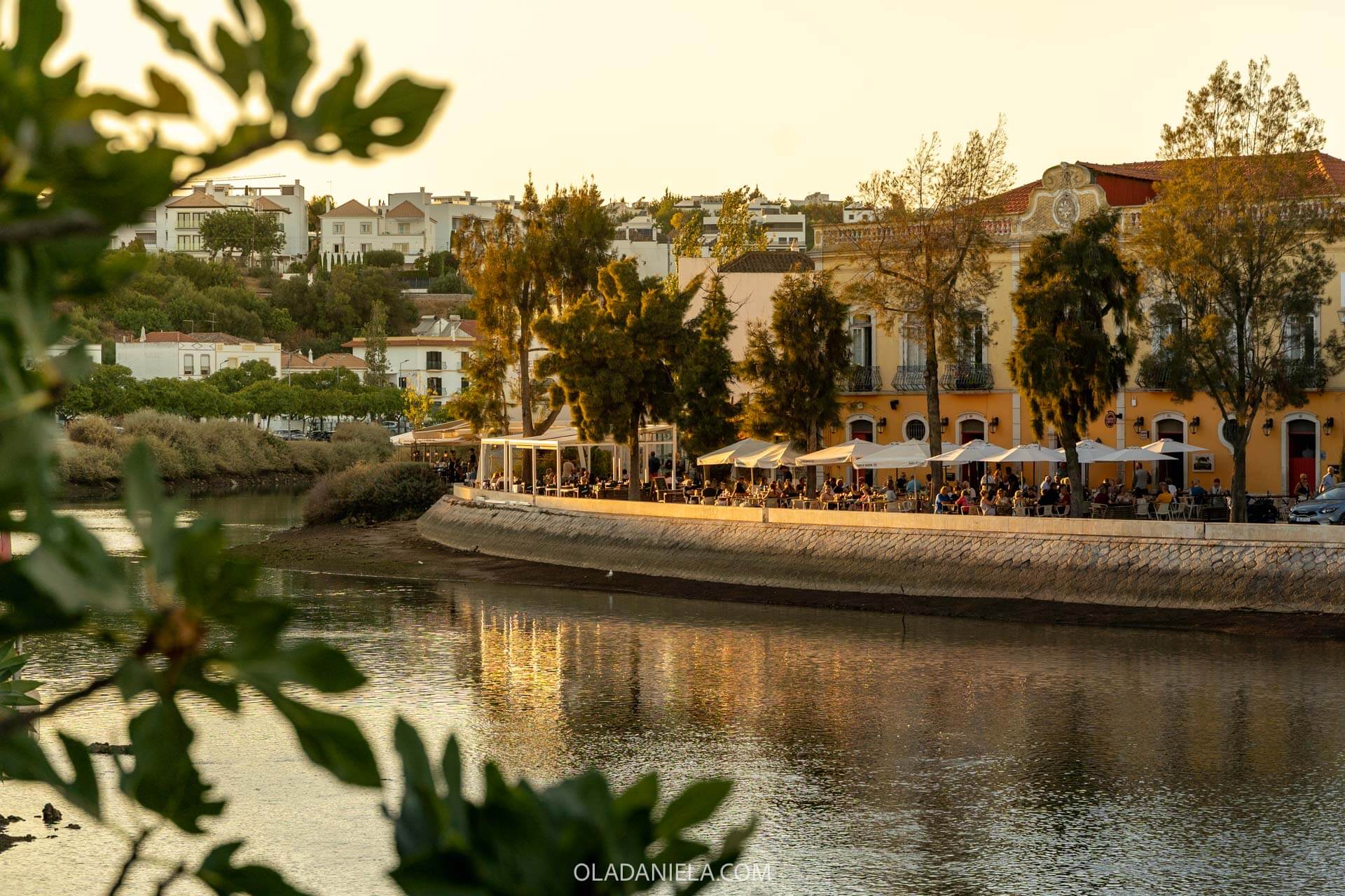 Outdoor restaurant seating set up along the edge of the scenic riverfront boardwalk in Tavira