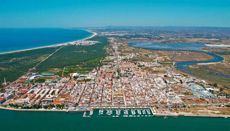 Aerial view overlooking the expansive golden sand beaches, coastal hotels, and clear blue waters of the Monte Gordo beachfront resort area
