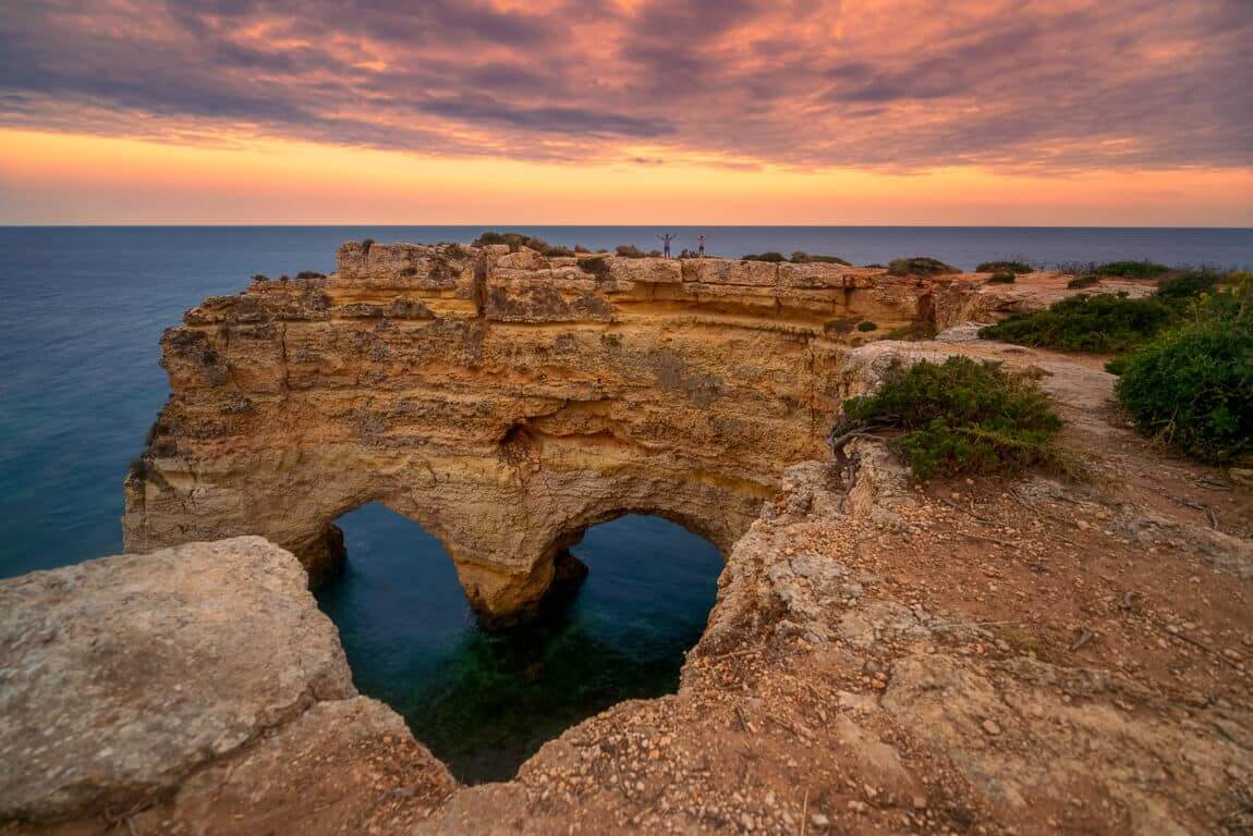 The iconic double limestone sea arches and crystalline turquoise waters of the world-famous Marinha Beach near Carvoeiro
